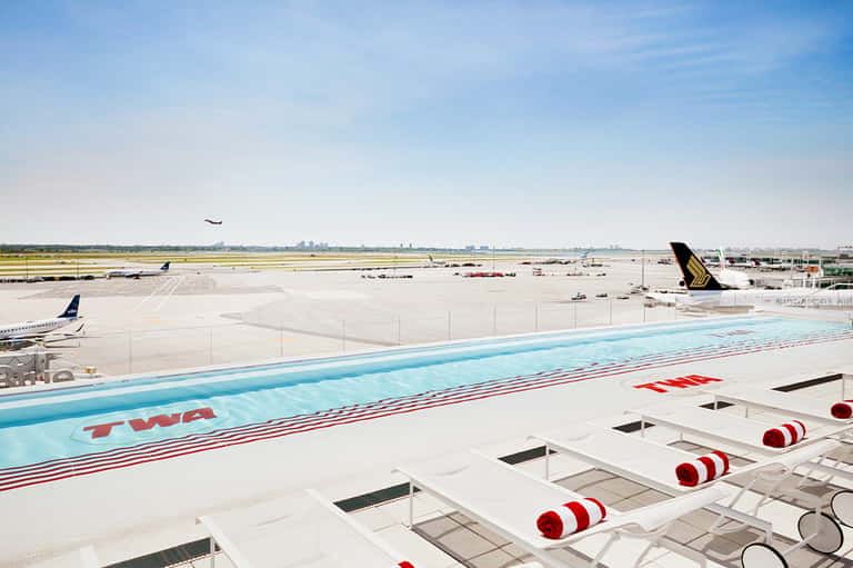 Aircraft wing and tail at airport with runway and aircraft in background during daylight