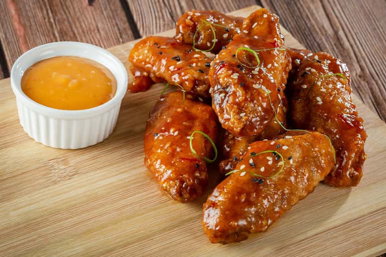 Glazed chicken wings with sesame seeds and green onions served with dipping sauce