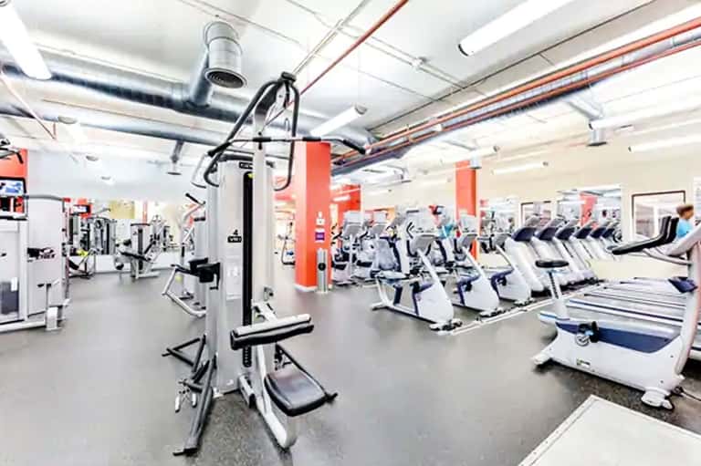Modern gym interior with exercise equipment, red support columns, and cardio machines