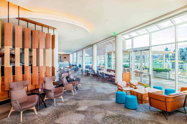 Modern hotel lounge with floor-to-ceiling windows, wooden design elements, and scenic outdoor view