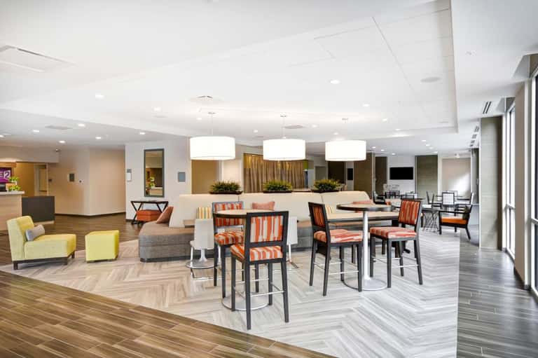 Contemporary hotel common area with lounge seating, dining tables, and reception desk