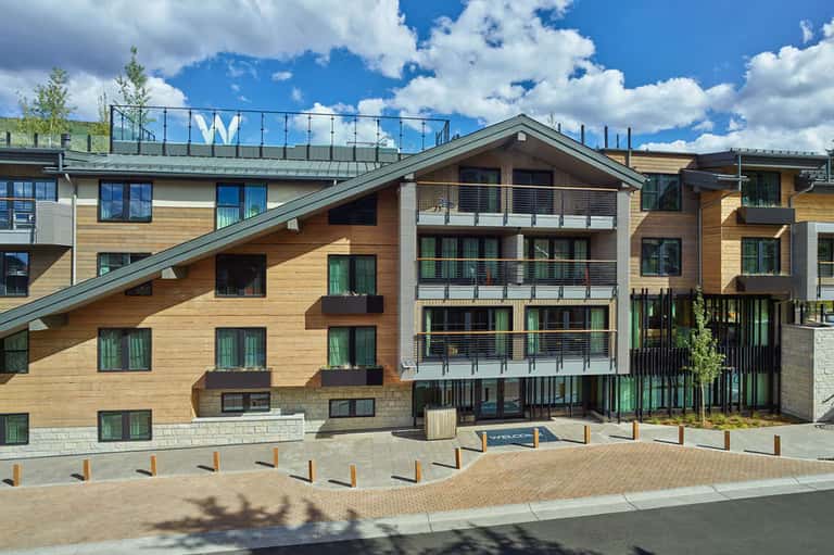 Contemporary wooden-clad residential building with multiple balconies and street-level plaza