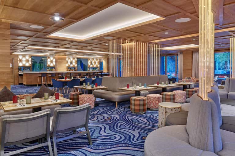 Upscale resort lounge with wooden ceilings, geometric patterns, and contemporary seating areas