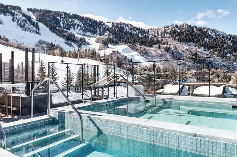 Mountain hot springs and pools with snowy slopes, forest views, and modern railings