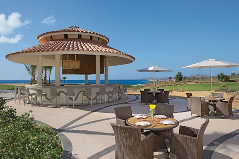 Beachfront grill pavilion with ocean views, dining tables, and tiki bar structure