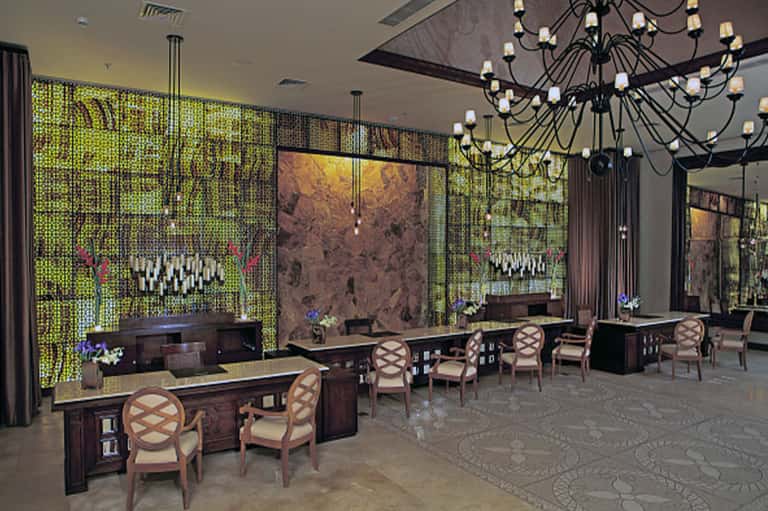 Luxury resort lobby with green lattice walls, elegant furnishings, and statement chandelier
