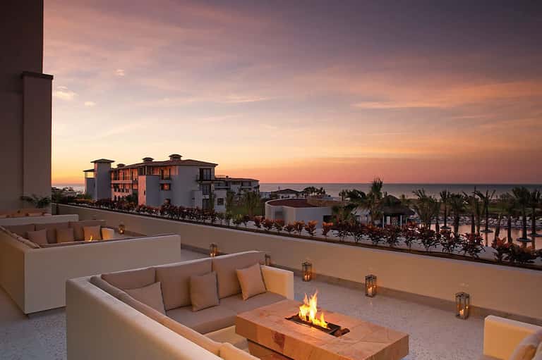 Sunset oceanview from elevated terrace with fire pit and modern coastal resort architecture