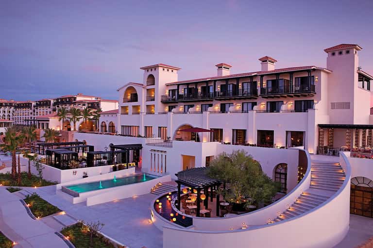 Luxurious resort courtyard at twilight with pool, architecture, and ambient lighting