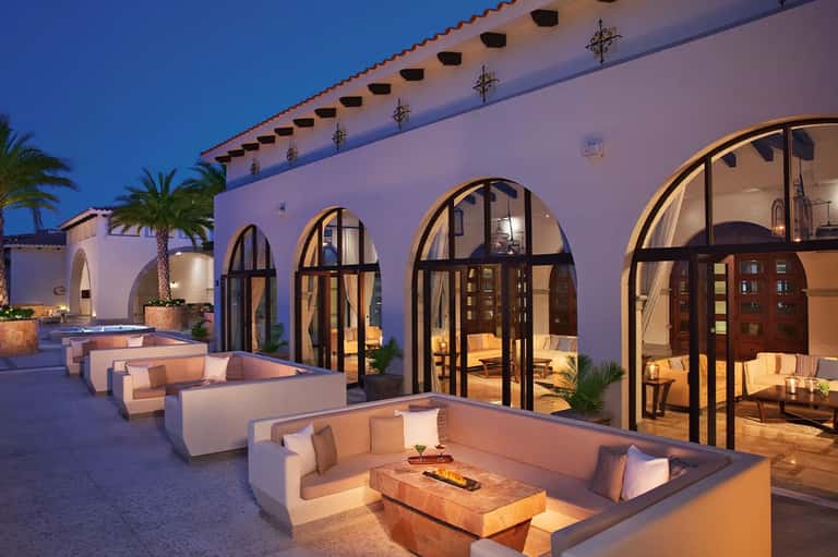 Upscale courtyard with arched windows, built-in seating, and ambient evening lighting