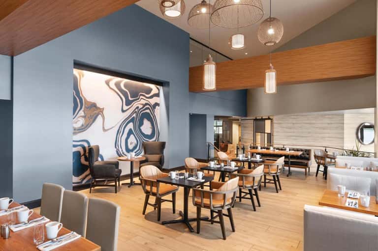 Modern restaurant dining room with blue accent wall, wooden beams, and pendant lighting