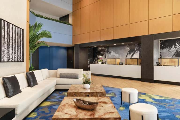 Modern hotel lobby with cream sofa, wooden reception desk, wood paneling, and contemporary design elements