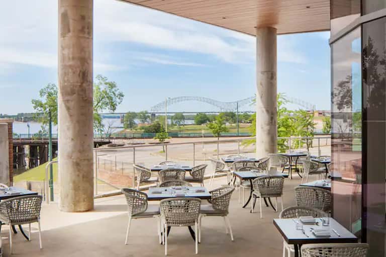 Waterfront restaurant patio with river bridge view and modern furnishings