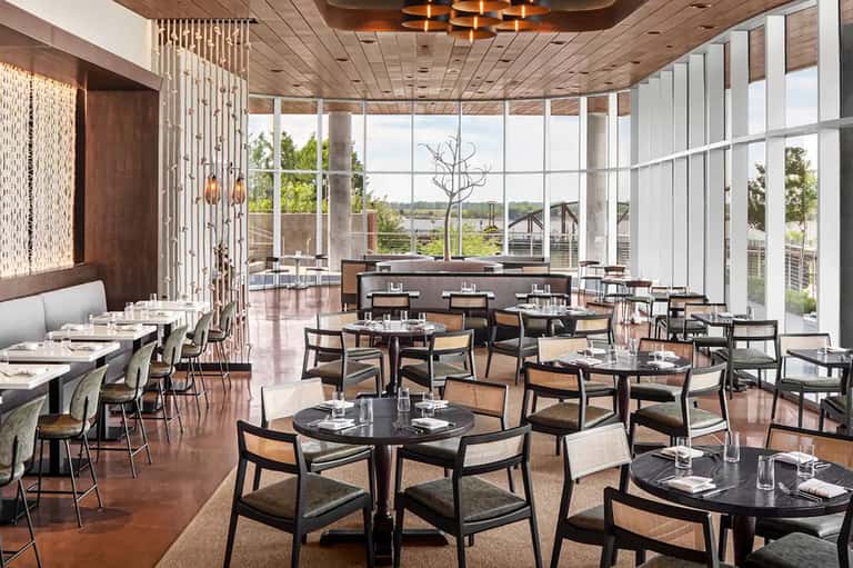Upscale restaurant dining room with large windows overlooking water and landscape