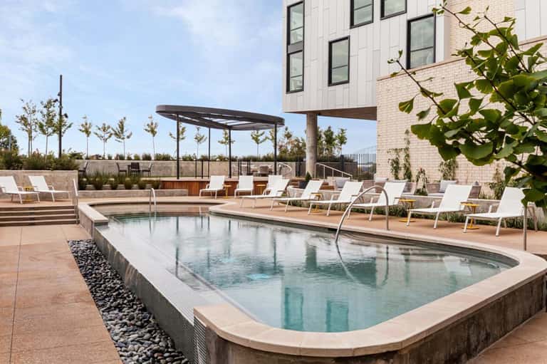 Rooftop pool with modern architecture, lounge chairs, and city views