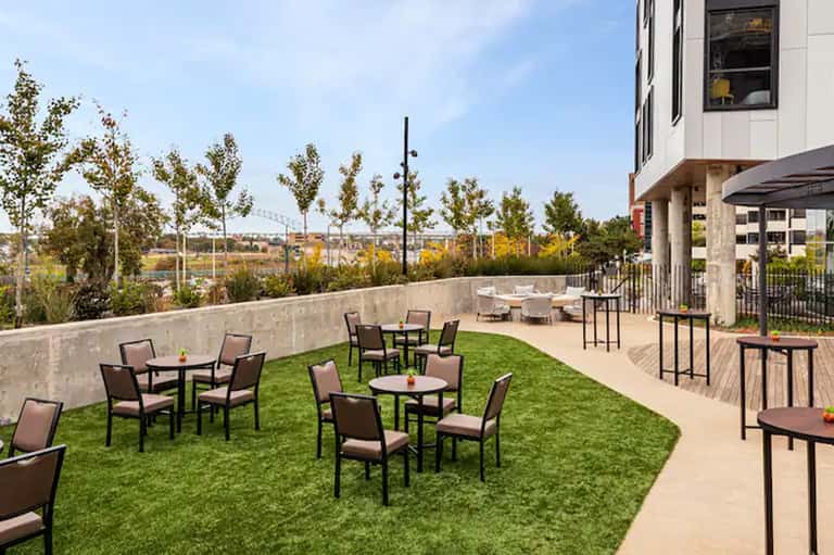 Urban hotel rooftop with artificial turf, seating areas, and distant bridge views