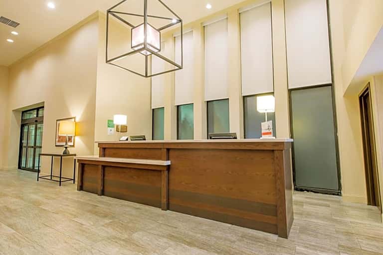Hotel lobby with wooden reception desk, warm lighting, and modern architectural design