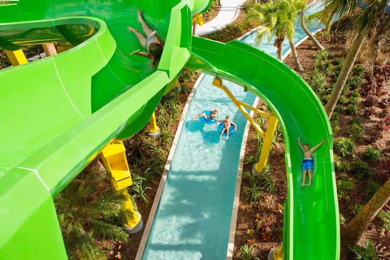 Green water slides at tropical resort with families enjoying the attraction