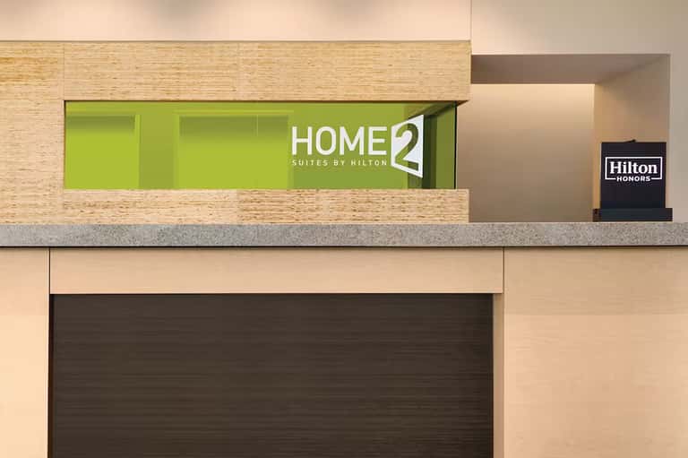 Home2 Suites by Hilton hotel check-in desk with lime green accent wall and modern design