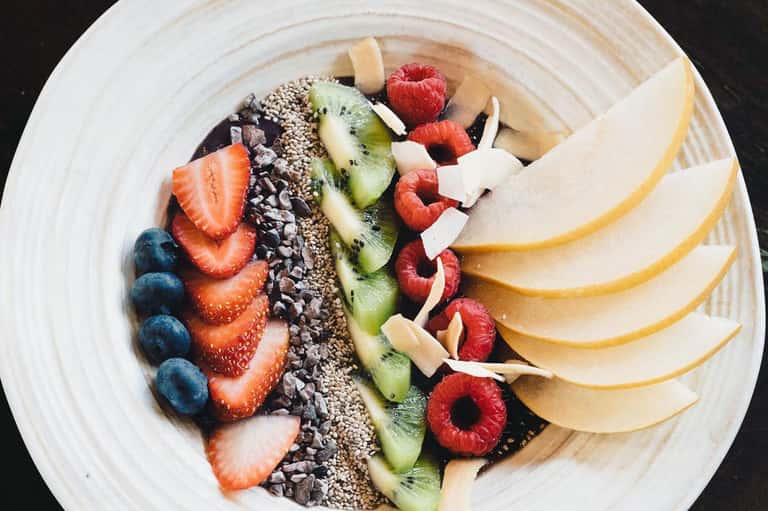 Artfully arranged fruit platter with berries, kiwi, apple slices, and coconut
