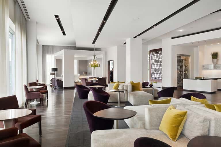 Contemporary hotel lobby lounge with cream and burgundy seating, yellow accent pillows