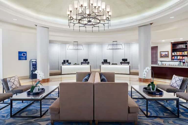 Elegant hotel lobby with circular chandelier, reception desks, comfortable seating, and polished floors