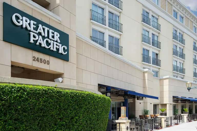 Greater Pacific hotel entrance with signage and outdoor patio seating