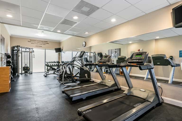 Modern gym with treadmills, exercise equipment, and motivational quote on wall
