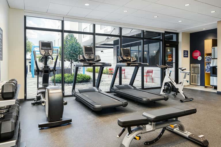 Fitness center with treadmills and stationary bikes near large windows
