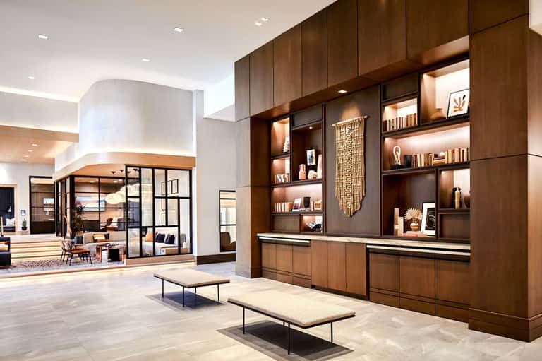 Modern hotel lobby with dark wood shelving and marble reception desk