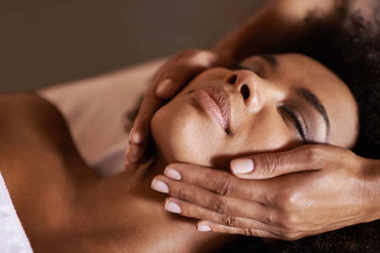 Close-up of spa massage with therapist's hands on client's face and shoulders