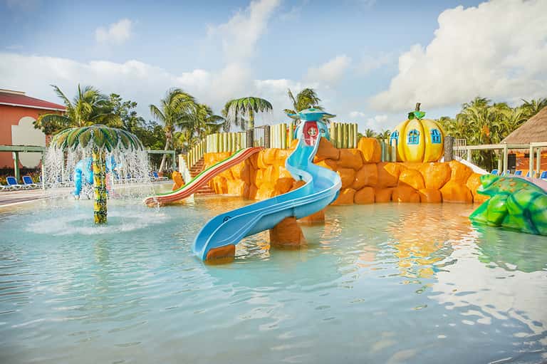 Colorful children's water park with bright orange rock formations and blue water slides
