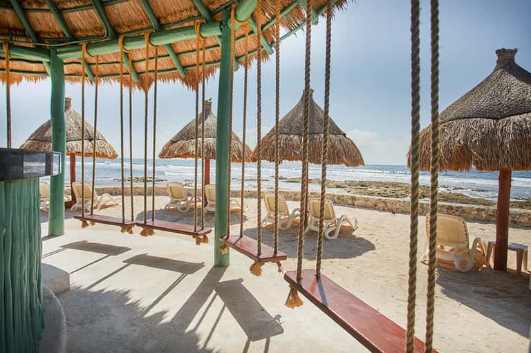 Beach cabana with rope swings, thatched umbrellas, and ocean view
