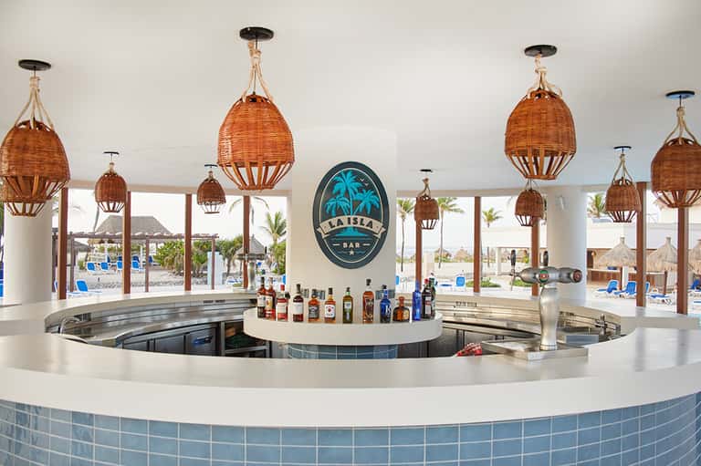 Beach bar with woven pendant lights, tropical views, and full liquor selection backdrop