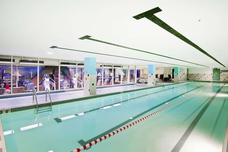 Indoor lap pool with lane dividers and large windows overlooking the street