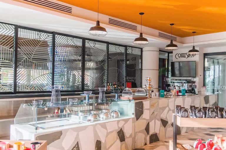 Modern coffee shop interior with geometric patterned windows and orange ceiling