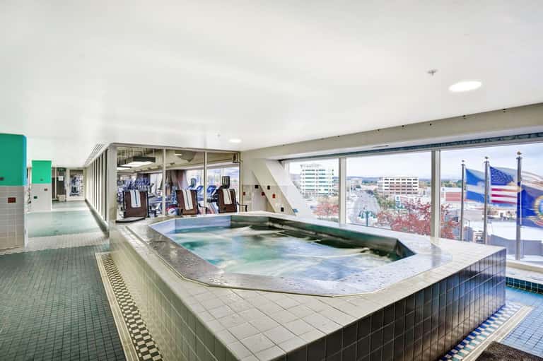 Indoor hot spring pool with colorful water and city views through large windows
