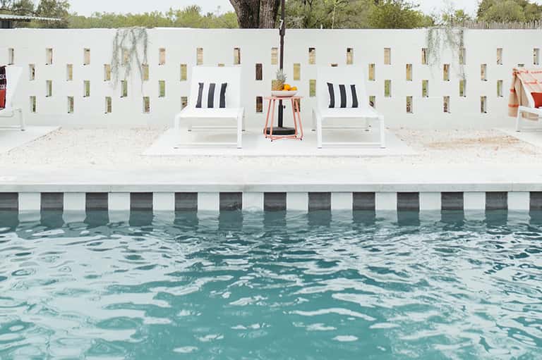 Poolside loungers with white wall backdrop and tropical vegetation