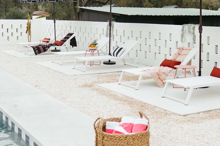 Beach lounge area with white chairs, umbrellas, and private sand section
