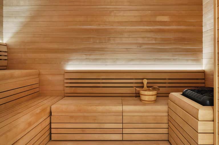 Wooden sauna interior with benches, bucket, and ambient lighting