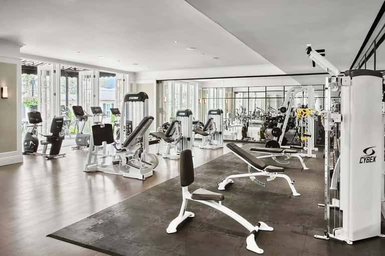 Modern gym with white and black equipment, including stationary bikes, weight machines, and exercise bikes