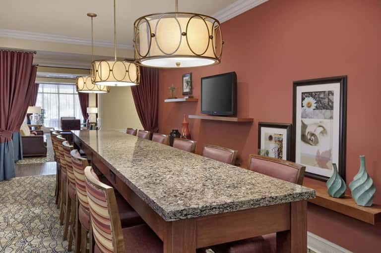 Elegant hotel meeting room with granite table, hanging pendant lights, and coral accent walls