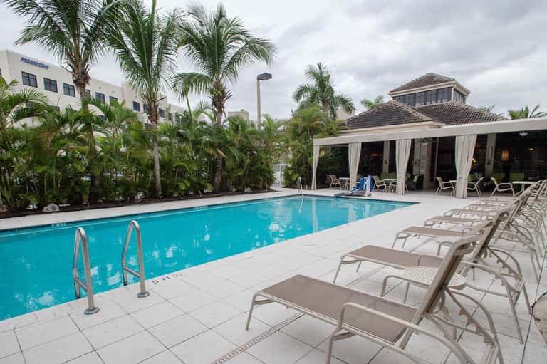 Rectangular pool with covered cabana, lounge chairs, and tropical landscaping