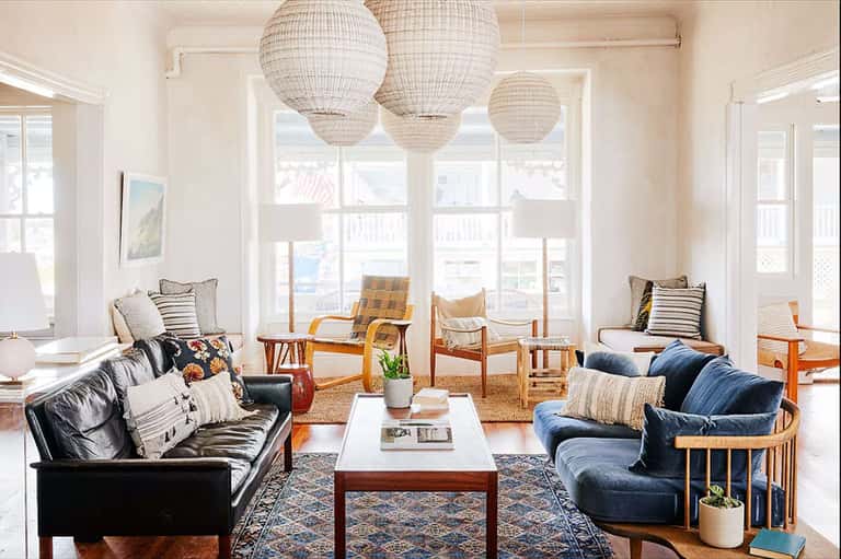 Bright coastal living room with leather sofas, woven pendant lights, and ocean views