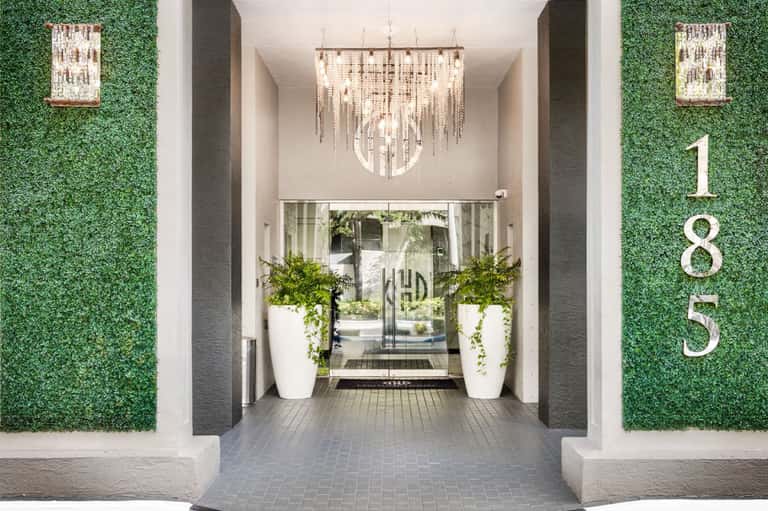 Modern building entrance with green living walls, elegant chandelier, and white planter urns