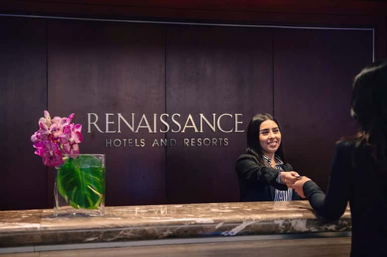 Hotel reception desk with Renaissance Hotels and Resorts branding and smiling staff member