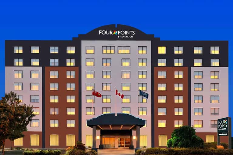 Four Points by Sheraton hotel exterior at dusk with illuminated windows and flags