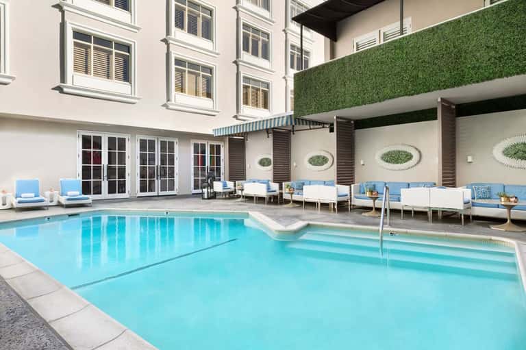 Indoor-outdoor hotel pool with blue lounge chairs and modern architecture