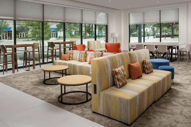 Contemporary lobby lounge with striped seating, round tables, and expansive glass windows
