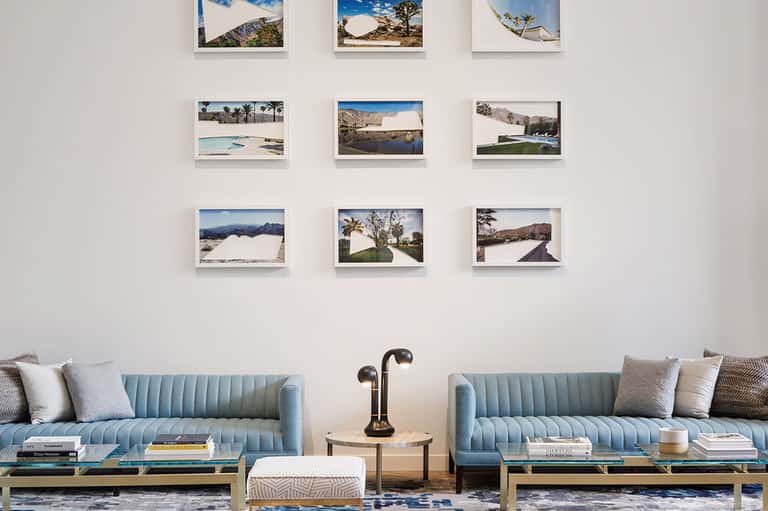 Hotel lobby with light blue velvet sofas and wall gallery of nine framed landscape photographs