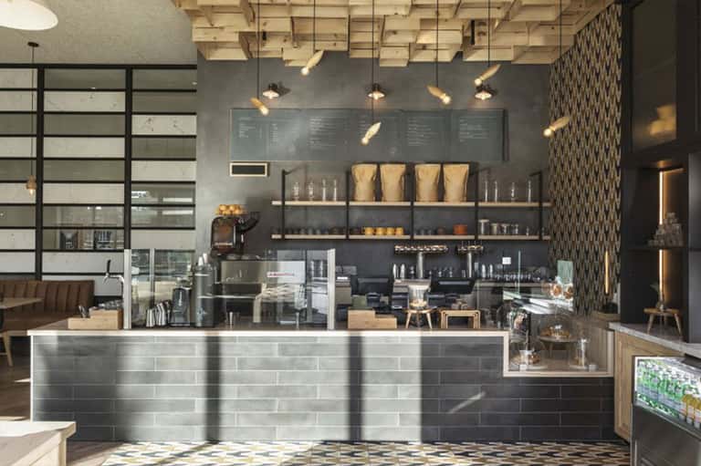 Modern hotel coffee shop interior with dark tile counter and espresso machine